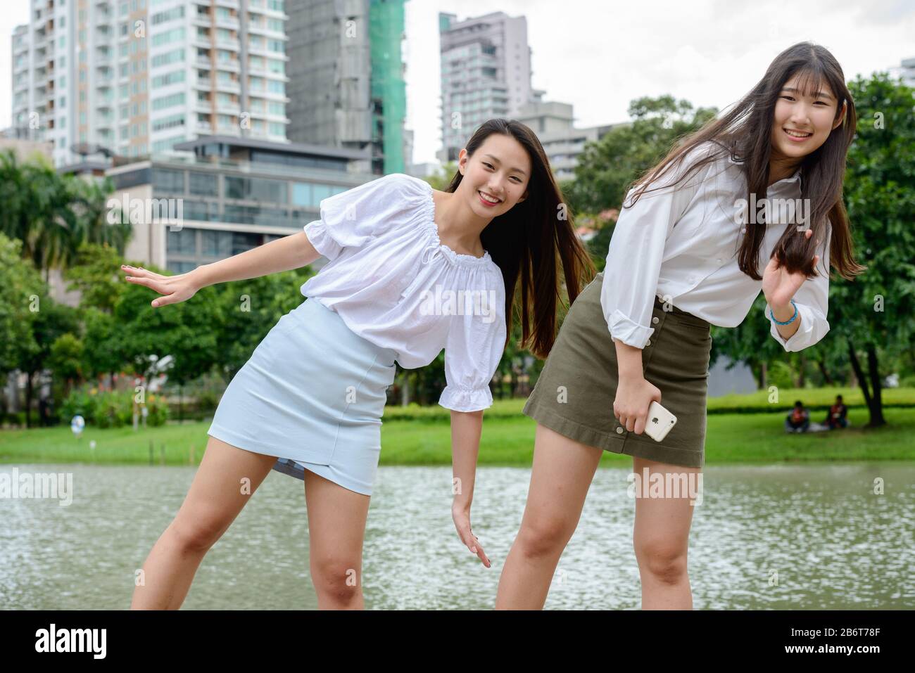 Zwei fröhliche junge, schöne asiatische Teenager-Mädchen, die zusammen im Park spielen Stockfoto