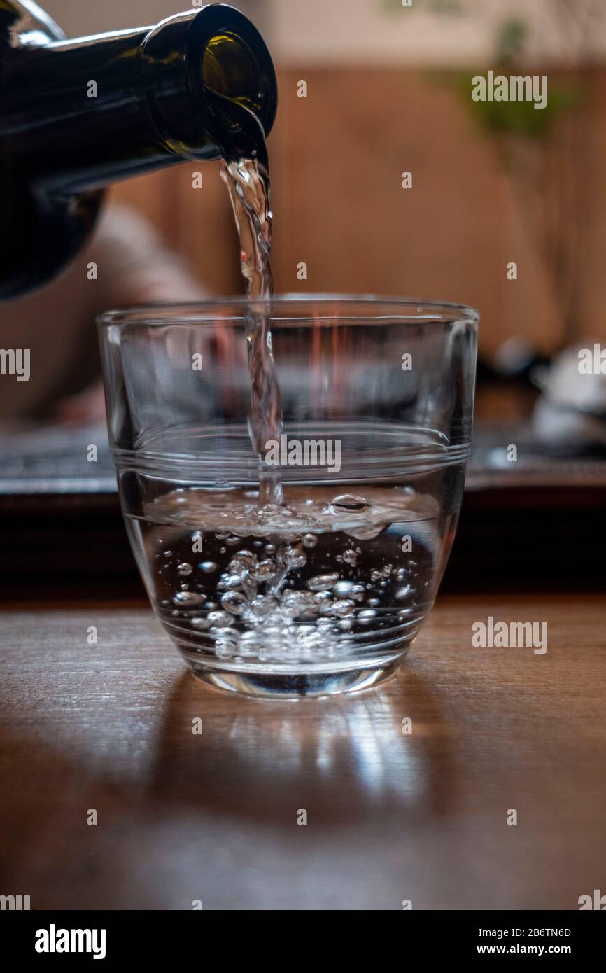 Gießt Wasser aus einer Flasche, ein Glas Stockfoto