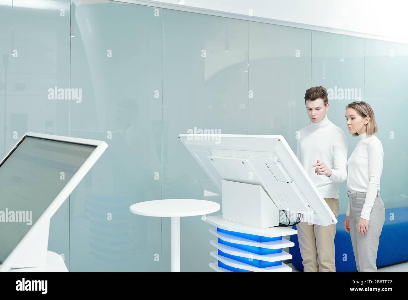 Junge Mitarbeiter des Informationszentrums nutzen eine große interaktive Anzeige, während sie Daten gemeinsam im Büro analysieren Stockfoto