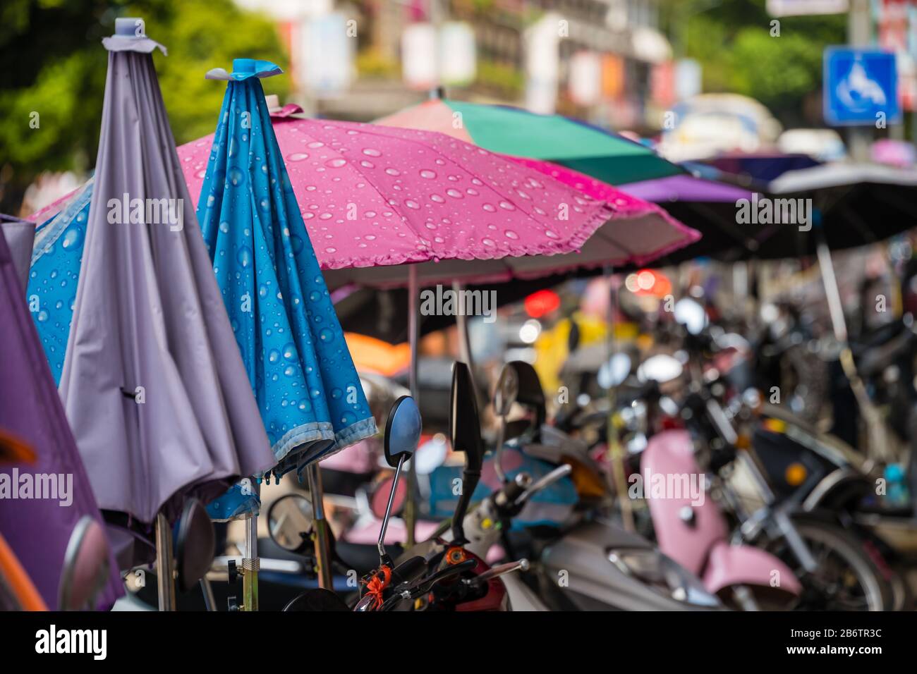 Yangshuo, China - August 2019: Reihe kleiner Motorräder und Roller, die auf einer Straße in der Yangshuo-Stadt in der Provinz Guangxi geparkt sind Stockfoto