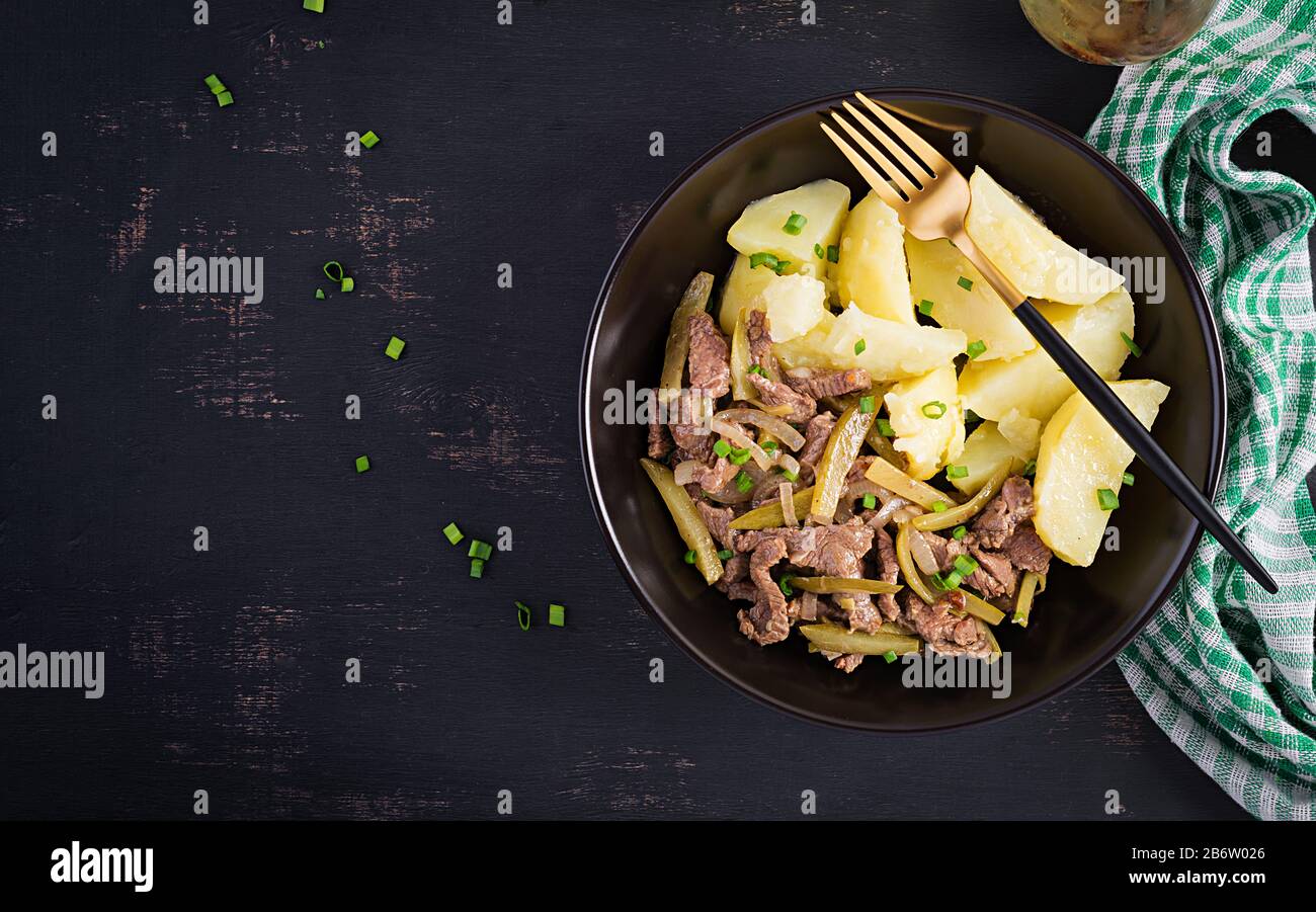 Einstechen Sie Rindfleisch, mit eingelegten Gurken bestücktes Rindfleisch im russischen Stil. Rinderstroganoff und gekochte Kartoffeln. Draufsicht, oben, flach Stockfoto