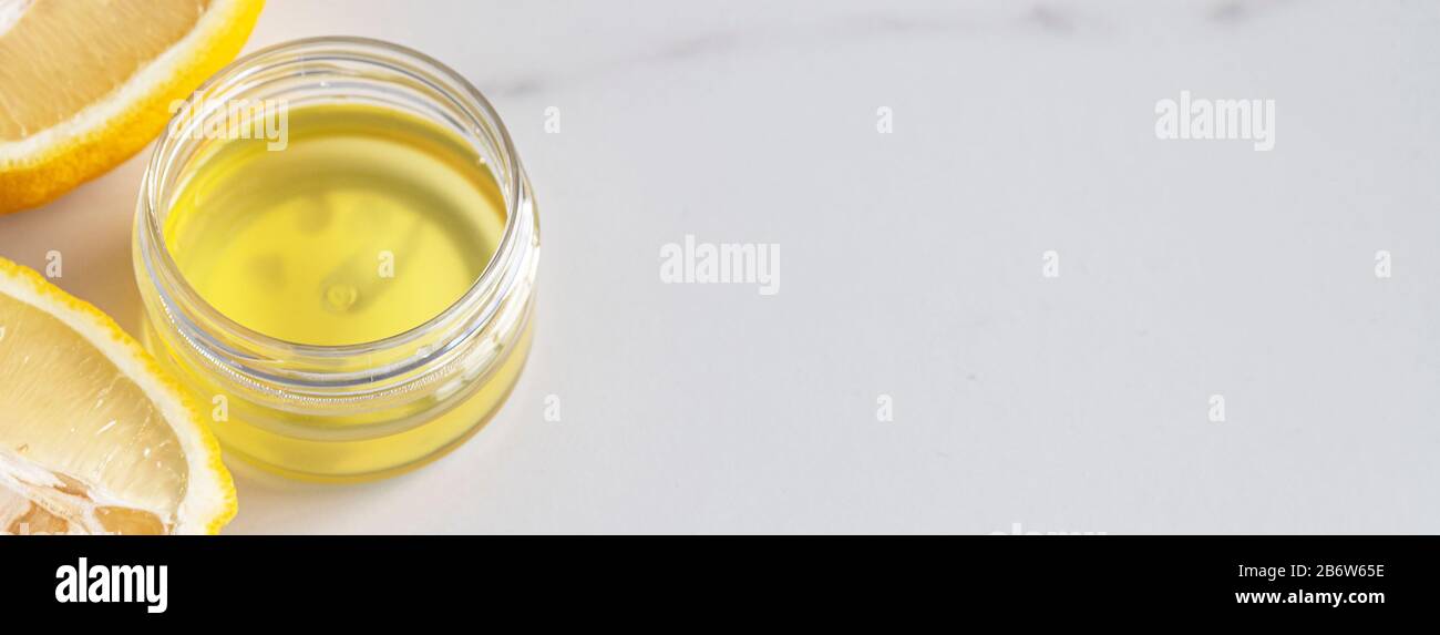 Kosmetisches Öl für Körper oder Gesicht mit Zitronenextrakt und Zitrusfrüchten auf grauem Marmorhintergrund mit Kopierraum. Konzept für natürliche organische Kosmetik Stockfoto
