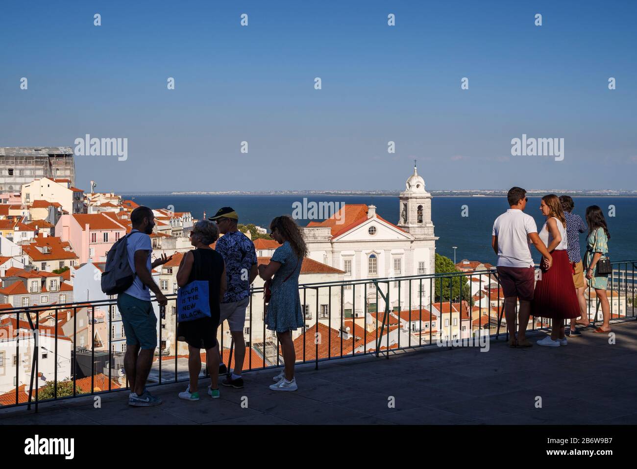 Touristen am Aussichtspunkt Largo das Portas do Sol und Blick auf alte Gebäude im historischen Viertel Alfama und auf den Fluss Tejo in Lissabon, Portugal. Stockfoto