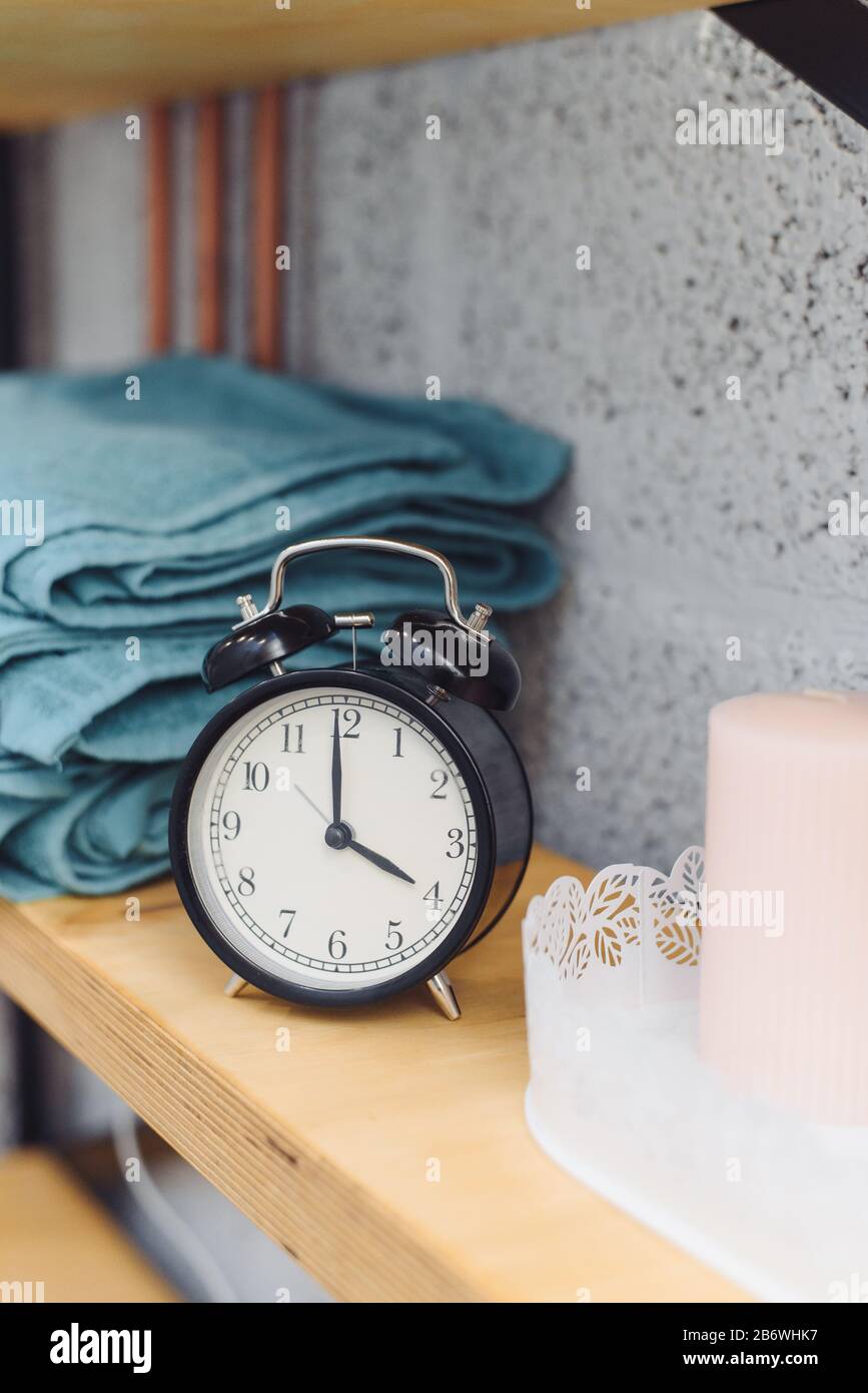 Massagezeit analoge schwarze Uhr auf einem Regal mit blauen Handtüchern und Wachskerzen. Das Konzept der Massageartikel. Stockfoto