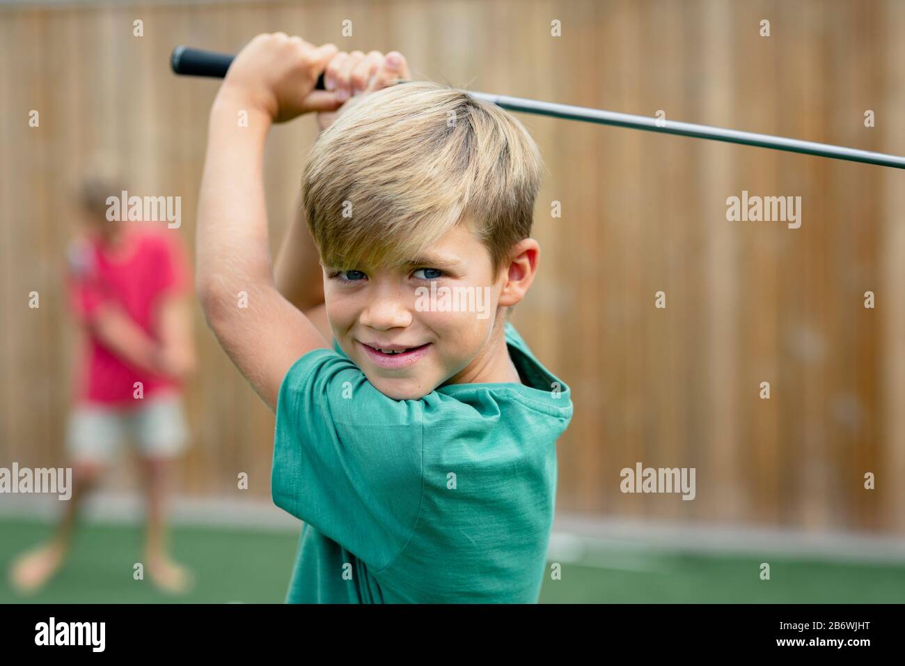Ein Vorderansicht Schuss eines jungen Golfers lächelnd und mit Blick auf die Kamera hält er einen Golfclub. Stockfoto