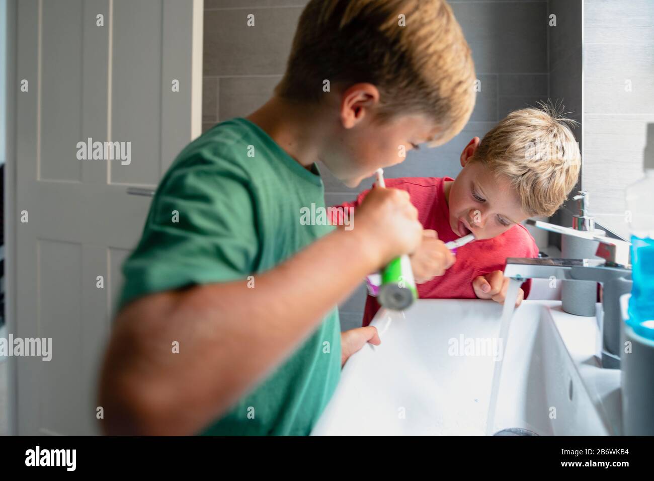 Ein Seitenansicht von zwei jungen Jungen, die ihre Zähne an der Spüle zusammenbürsten. Stockfoto