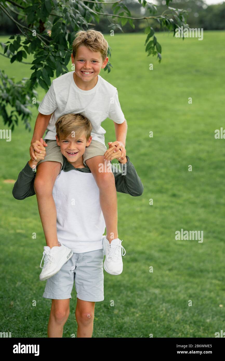 Ein Schuss von zwei jungen Jungen, die zusammen spielen, sitzt ein Junge auf den Schultern seiner Brüder. Stockfoto