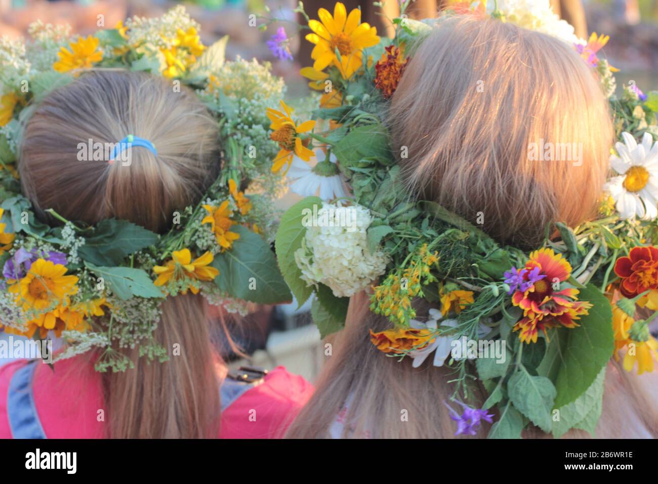 Zwei Mädchenköpfe in Kronen von Wildblumen, Nahaufnahme, Rückansicht. Ukrainischer Blumenkranz für Ivana Kupala auf dem Midsummer fest Stockfoto