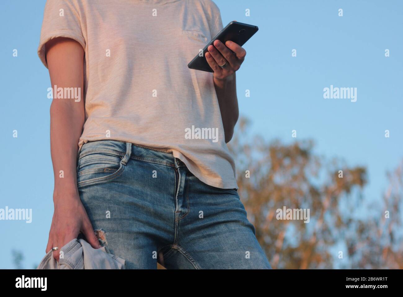 Junge Frau mit Smartphone im Freien und in der Natur. Nahaufnahme des Smartphones. Mädchen mit Handy im Sommerpark Stockfoto