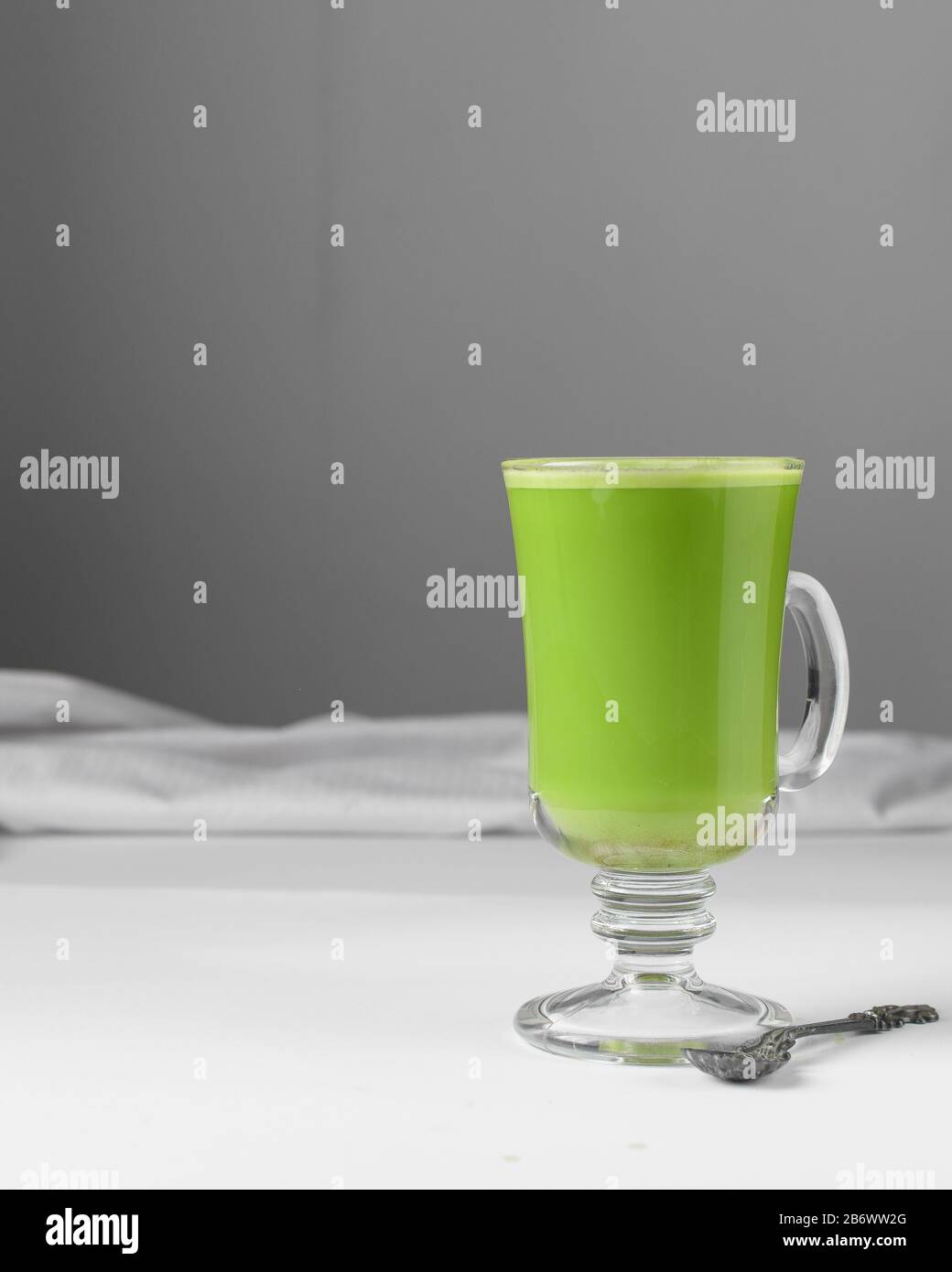 Grüne Latte in Glaskasse, Matchlatte mit Schaum auf weißem Tisch Stockfoto