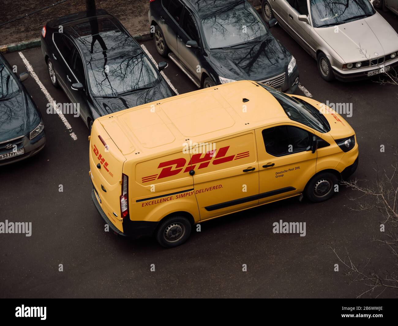 Moskau, Russland - 11. März 2020: DHL Deutsche Post Kurier in gelb-roter Uniform in der Nähe von Kleinbus mit Firmenlogos. Die DHL International GmbH ist Weltlarg Stockfoto