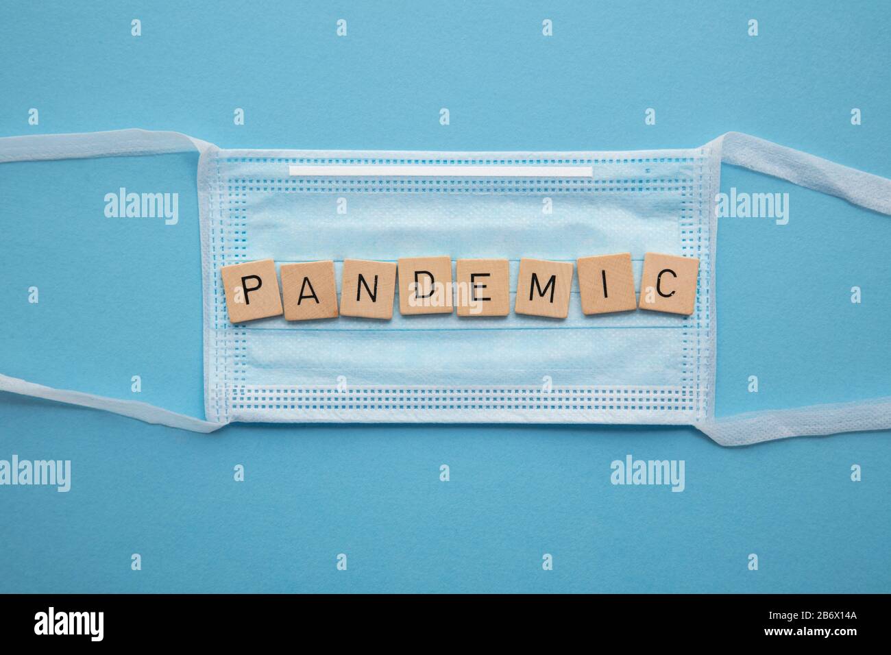 Medizinische Gesichtsmaske mit dem Wort Pandemie auf blauem Hintergrund Stockfoto