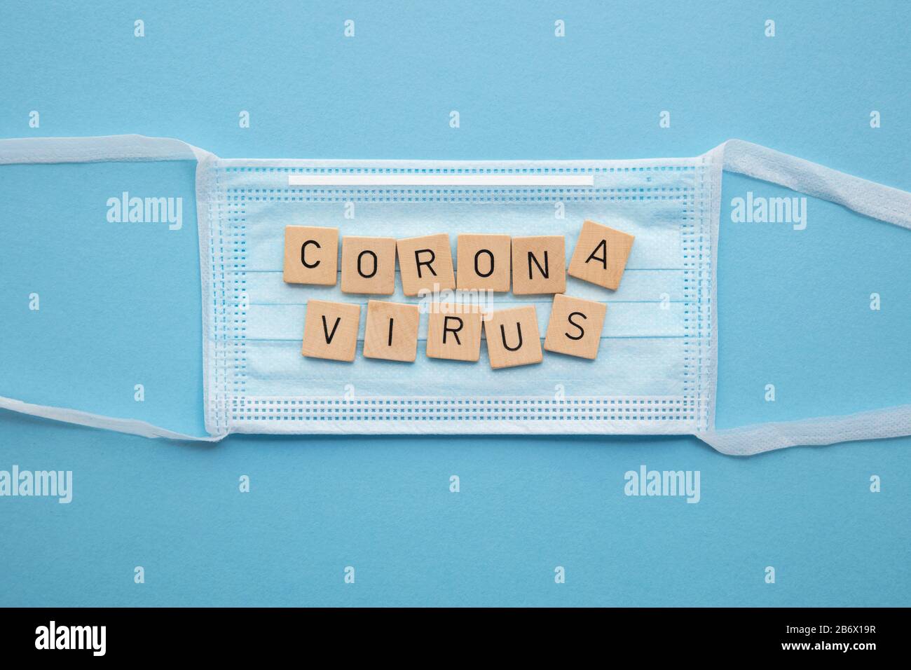 Medizinische Gesichtsmaske mit dem Wort Coronavirus auf blauem Hintergrund Stockfoto