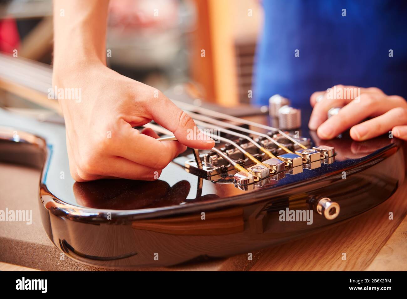 Hand of Guitar Maker arbeitet an E-Gitarre mit einem Inbusschlüssel Stockfoto