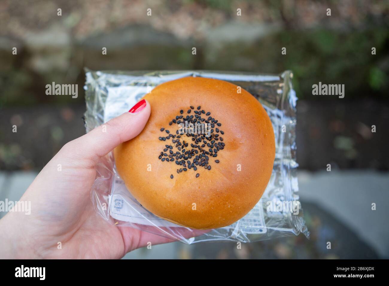 Die Hand einer Frau, die einen Anpan, japanisches rotes Bohne, hält, kaufte sich von einem Convenience-Geschäft in Shinjuku, Tokio, Japan. Stockfoto