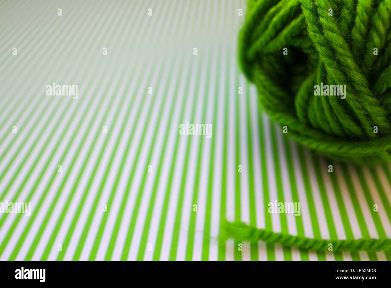 Grüner Garnball auf grün gestreiftem Hintergrund. Stockfoto