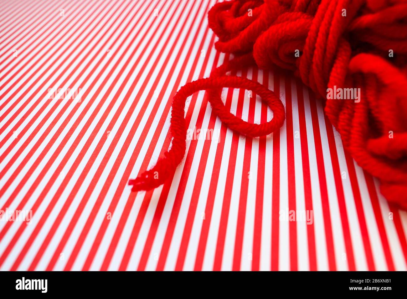 Roter Garnball auf rot gestreiftem Hintergrund. Stockfoto