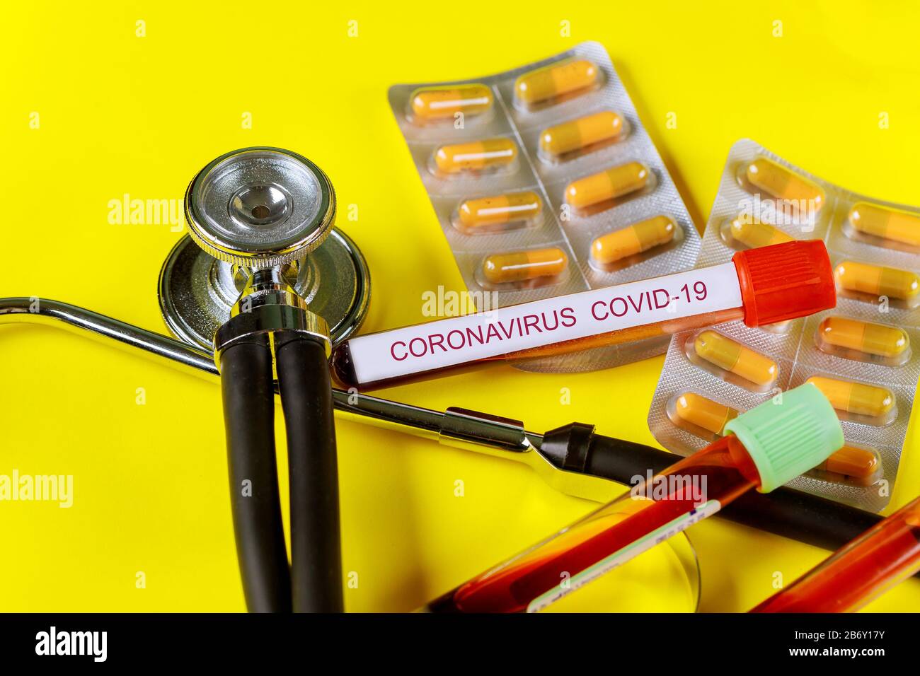 Röhreninfizierte Blutprobe COVID 2019. Corona-Virus überbrechende Medizentabletten auf Stethoskopen Stockfoto
