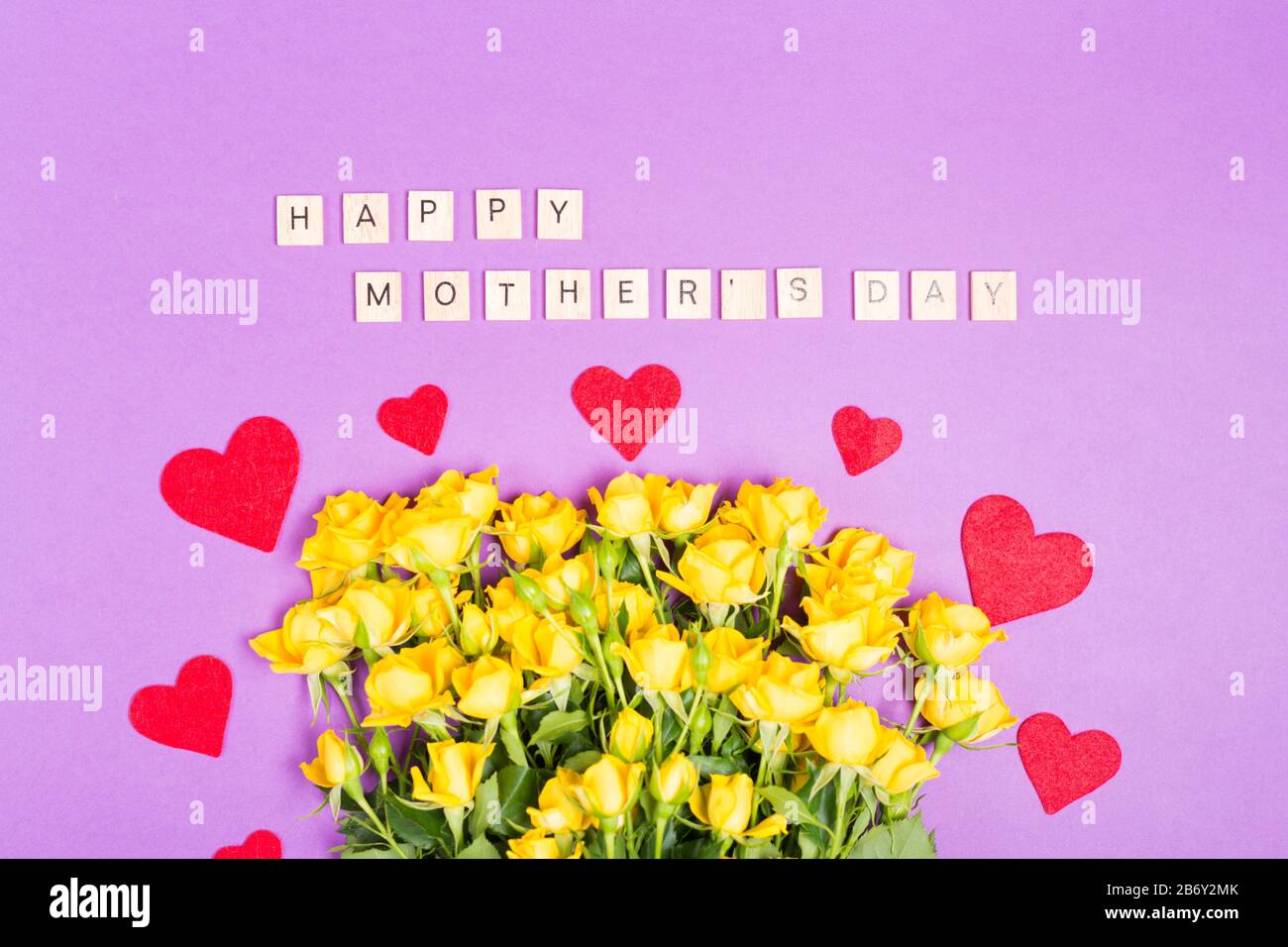 Fröhlicher Muttertag mit gelben röhrlichen Blumen auf violettem Tischhintergrund Draufsicht mit freiem Platz Kopierraum romantisch Stockfoto