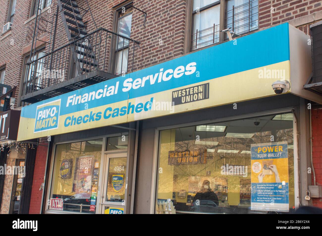 Geschäft vor einem Payomatic Scheckkassierkiosk in Inwood, Manhattan, New York. Bietet Finanztransaktionen für Personen ohne Bankkonten. Stockfoto