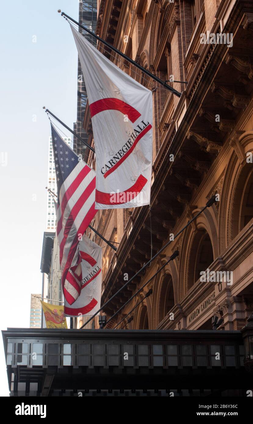 Das Logo-Banner der Carnegie Hall hängt neben der amerikanischen Flagge über dem Eingang zur Carnegie Hall, einer amerikanischen nationalen Sehenswürdigkeit Stockfoto