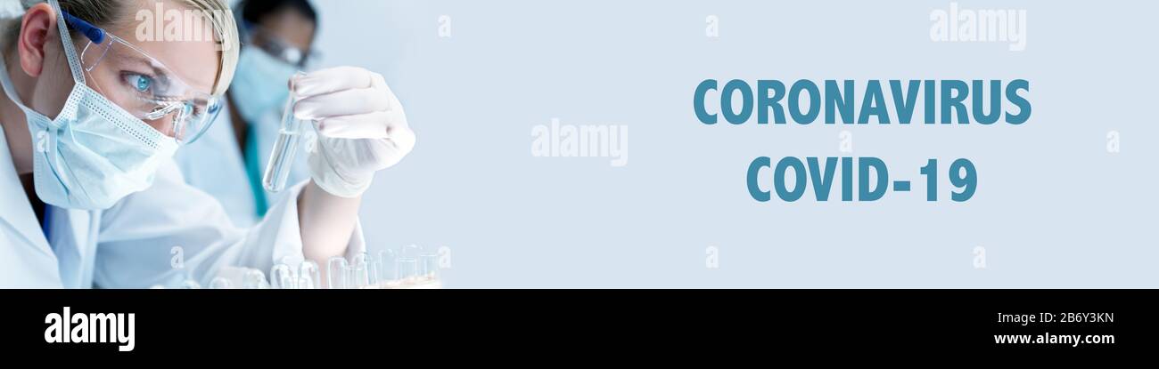 Panorama Frau medizinische oder wissenschaftliche Forscherin oder Ärztin mit Gesichtsmaske und Blick auf ein Reagenzglas in einem Labor mit ihrem asiatischen Kollegen o Stockfoto