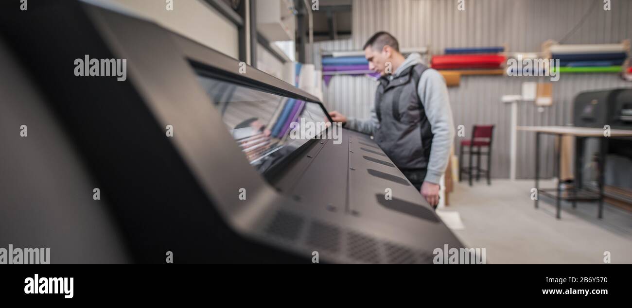 Techniker, der den ein- und Ausgabestatus auf der Touchscreen-Monitorstation auf der Vorderseite des Digitaldruckereibüros überprüft Stockfoto