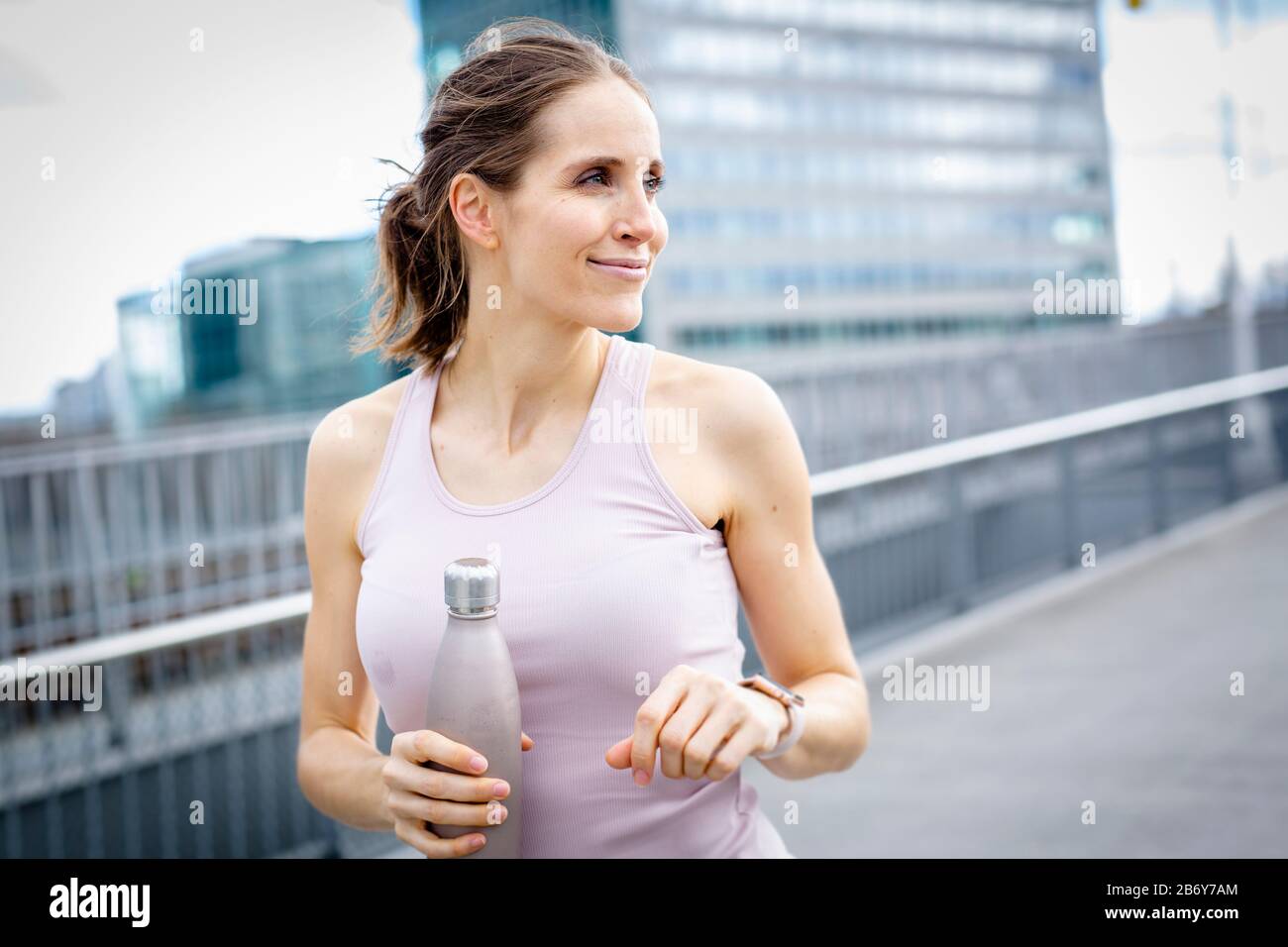 Junge Athletin nach dem Joggen mit Wasserflasche in der Hand.junge Sportfrau nach Joggen mit Wasserflasche in der Hand. Stockfoto