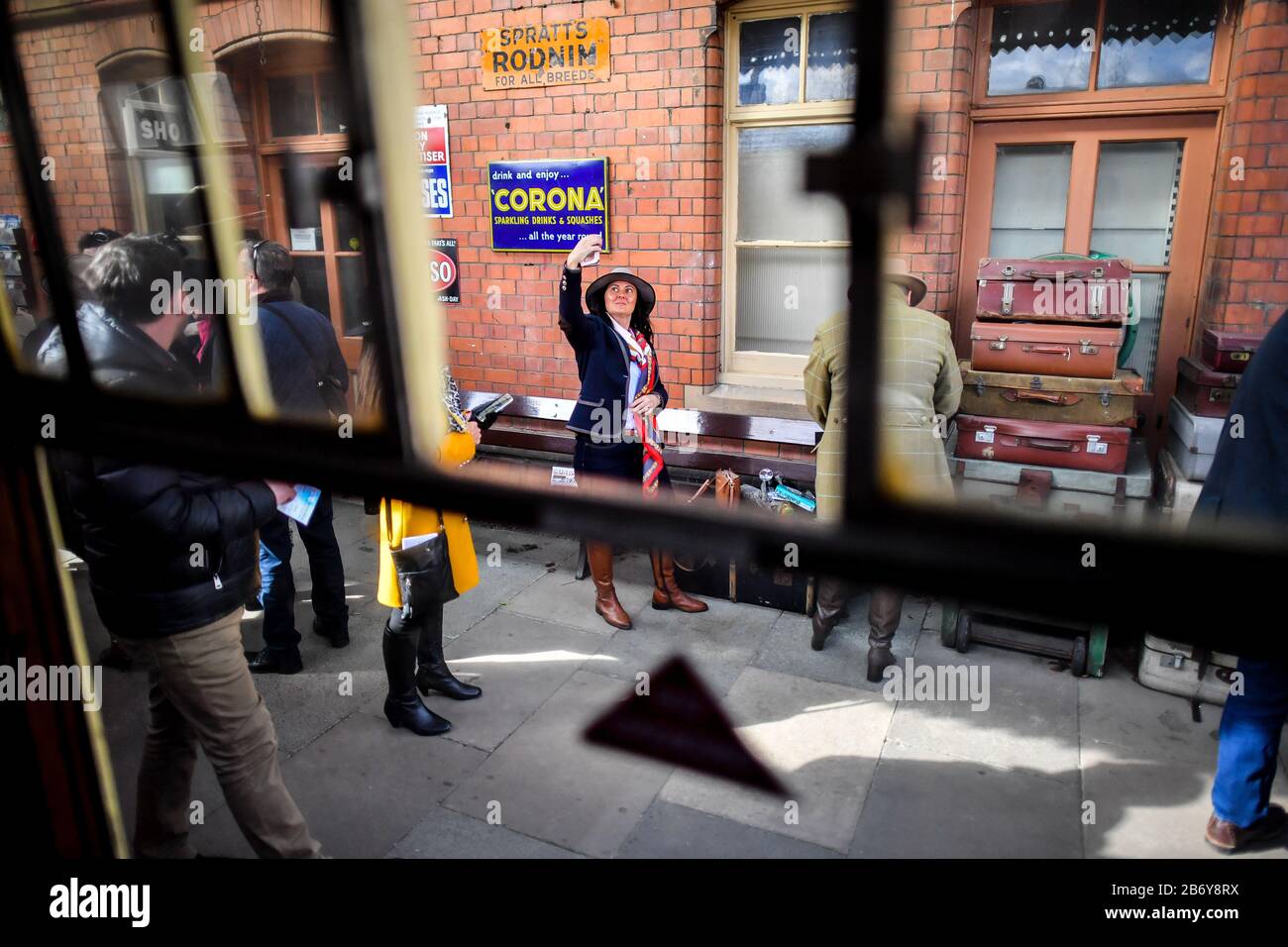 Ein Rennbote nimmt einen selfie auf den Bahnsteig am Bahnhof Toddington in Gloucestershire, wo die Leute einen Dampfzugdienst zu Cheltenham Rennen, die während des Festivals laufen, fangen. Stockfoto