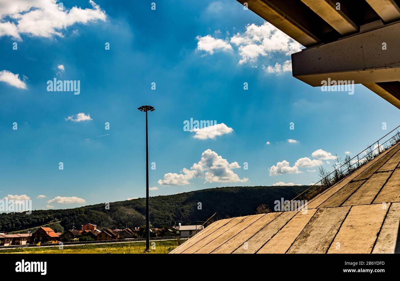 Kreuzung unter der Brücke mit Lichtpfahl und Wohngebiet und Wald im Hintergrund Stockfoto