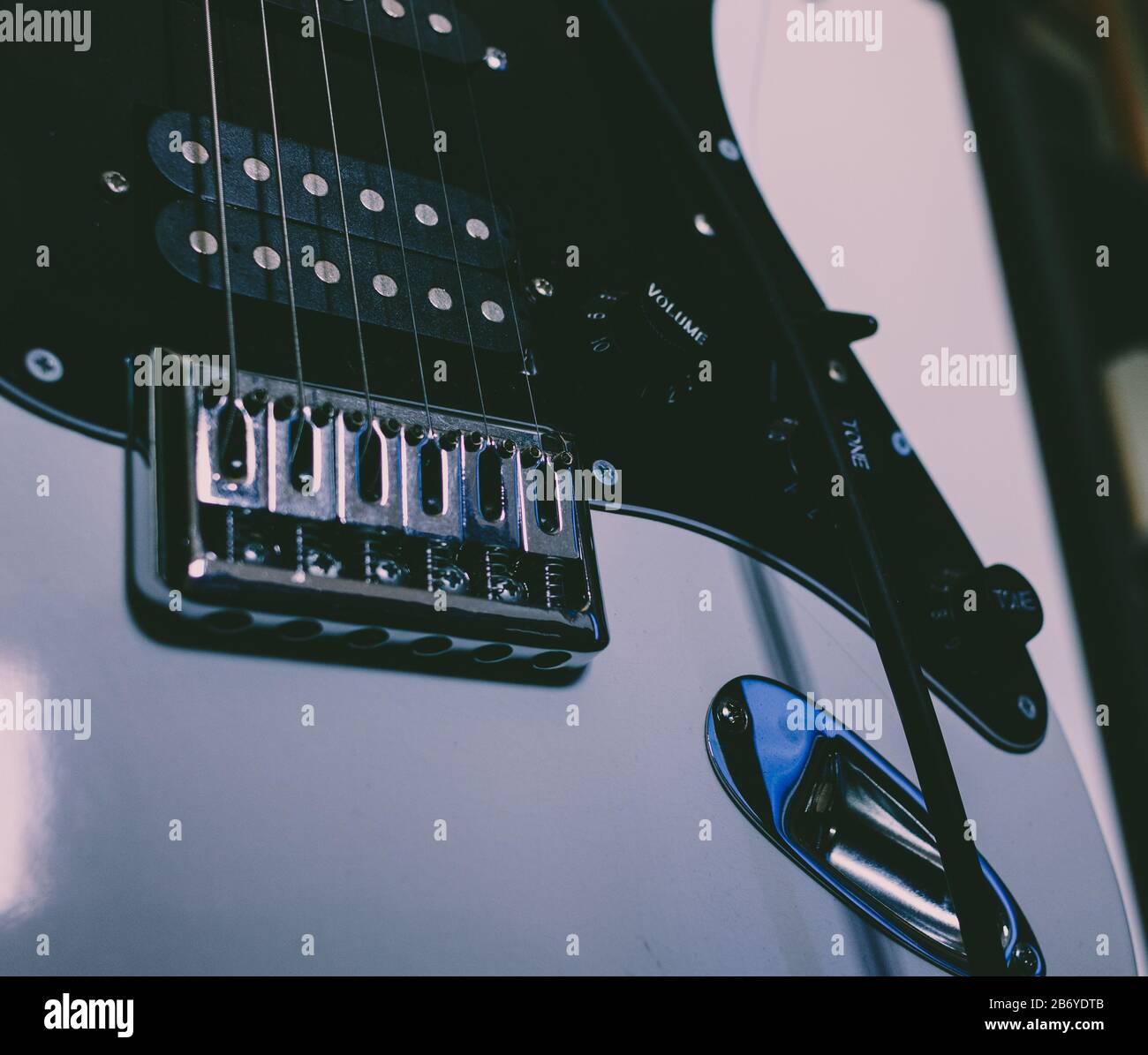 Dunkle Ansicht einer unteren Hälfte der E-Gitarre mit Bridge, Tonabnehmern, Saiten und Tasten zur Lautstärkeregelung und Tonregelung Stockfoto
