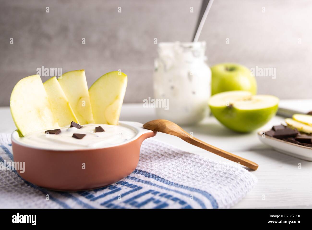Frühstück Bio-Joghurt in einem Mixbecher mit reiner Schokolade und frischen Apfelscheiben Stockfoto
