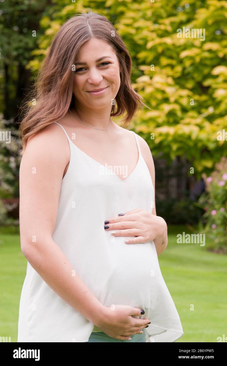 Schöne schwangere junge Frau, die ihren Baby-Bump zauste Stockfoto