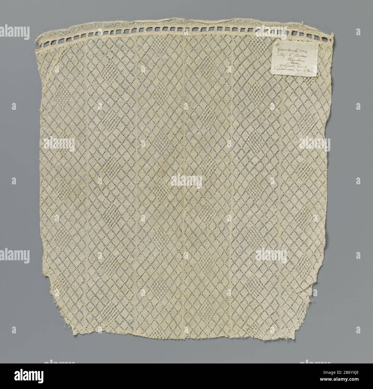 Kleedje van stroken kloskant traf sich in ruitenpatroon Kleedje van zes aan elkaar genaide stroken naturellkleurige kloskant. Vierkant traf sich mit afgeronde hoeken, die aan één kant traf een ingezet stukje weer recht zijn gemaakt. Langs deze kant is het kleedje afgewerkt met een opengewerk Rand met blokjes die ontstaan door dubbele vlechtjes en Stockfoto