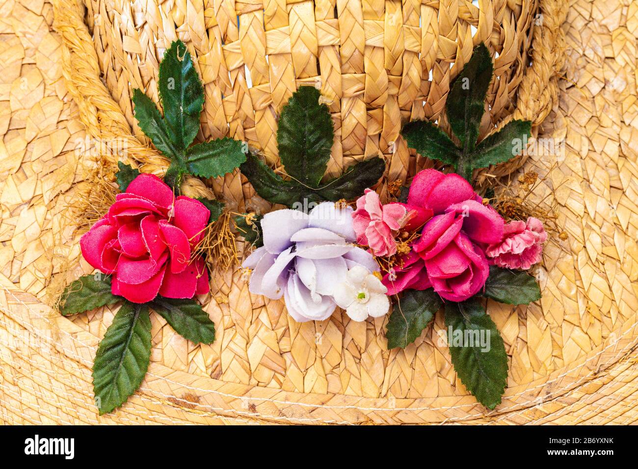 Künstliche Blumendekoration auf einem alten Strohhut für Damen Stockfoto
