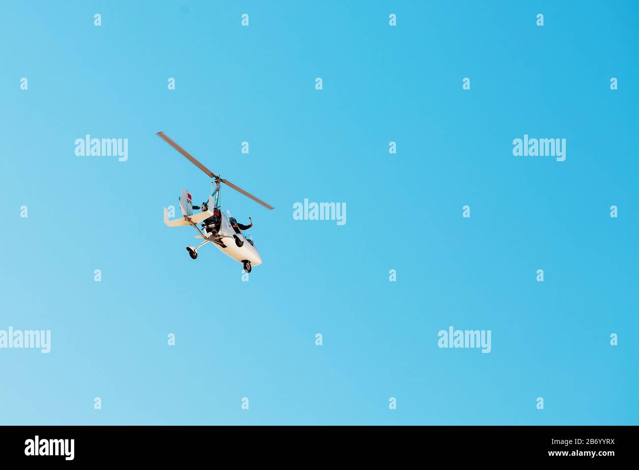 Weißer kleiner Doppel-Kreisel autogyro ohne Kabine gegen den blauen Himmel. Flugreisen für Touristen. Mini-Hubschrauber Stockfoto