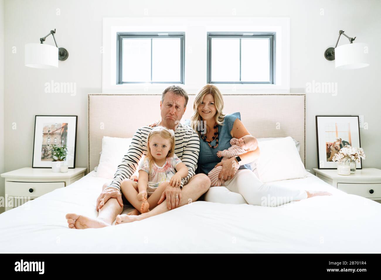 Porträt einer Familie, die zusammen auf einem Bett sitzt und dumme Gesichter macht Stockfoto