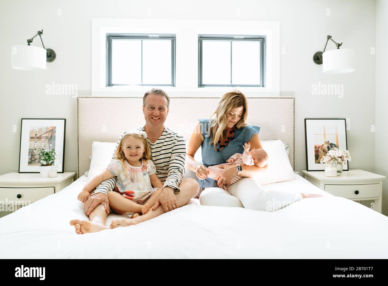 Gerade auf Porträt einer vierköpfigen Familie sitzen zusammen auf einem Bett Stockfoto