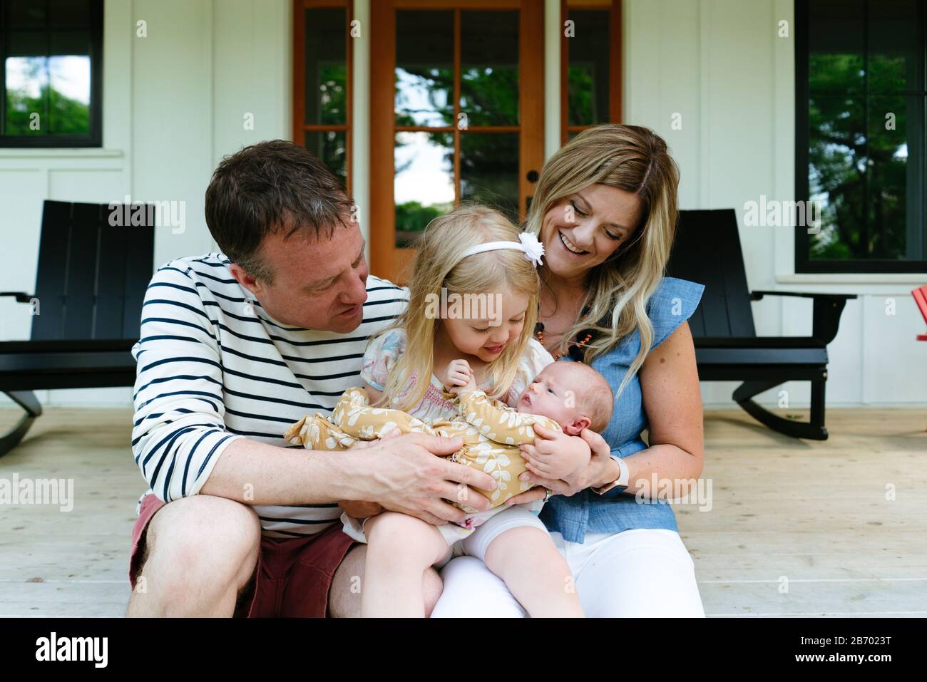 Eine neue Familie sitzt zusammen auf einem modernen Bauernhaus Veranda Stockfoto