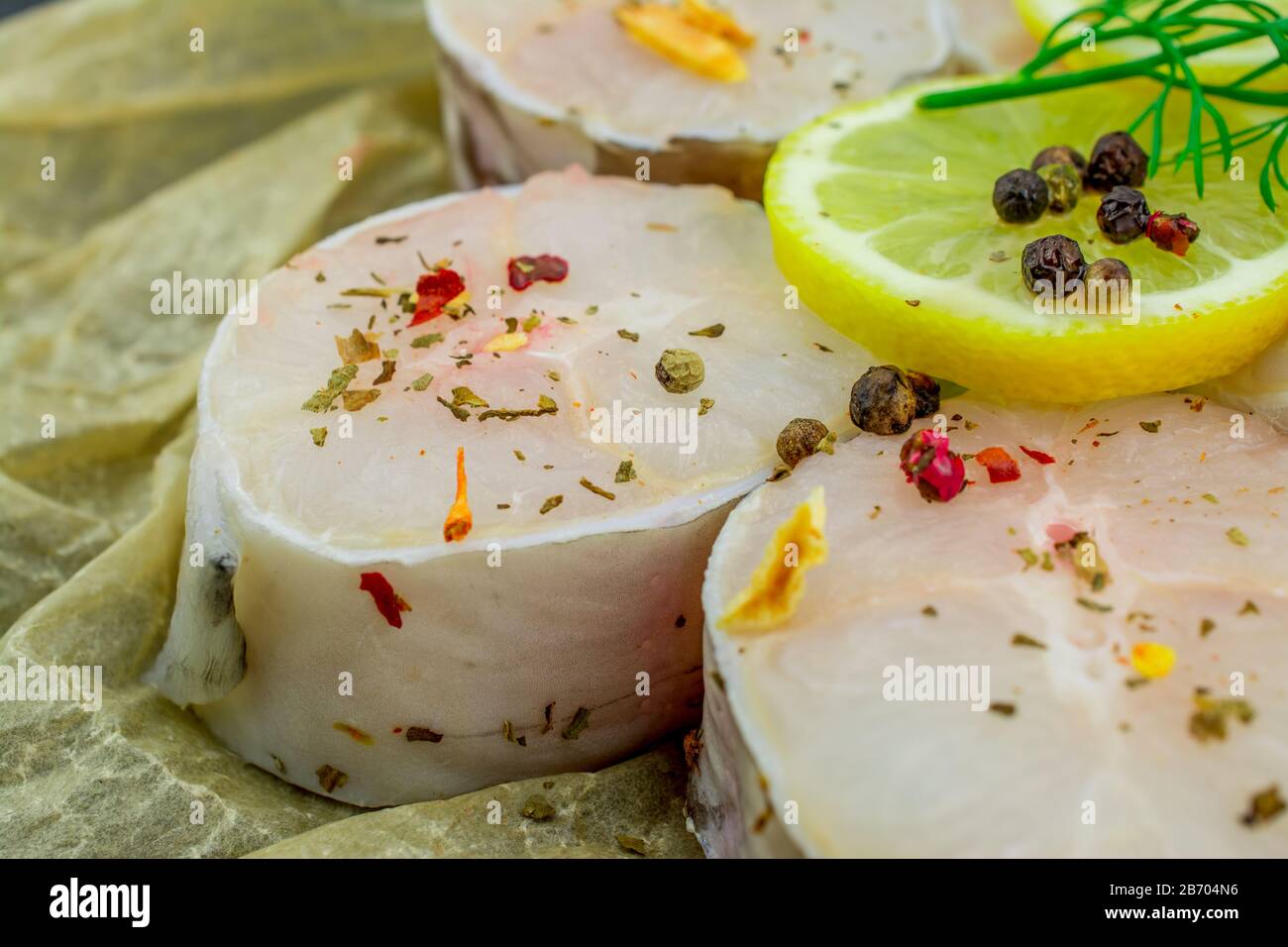 Frische Fischfilets aus Kongeraal, Zitronenkräuter, Pfeffer, Salz auf schwarzem Grund Stockfoto