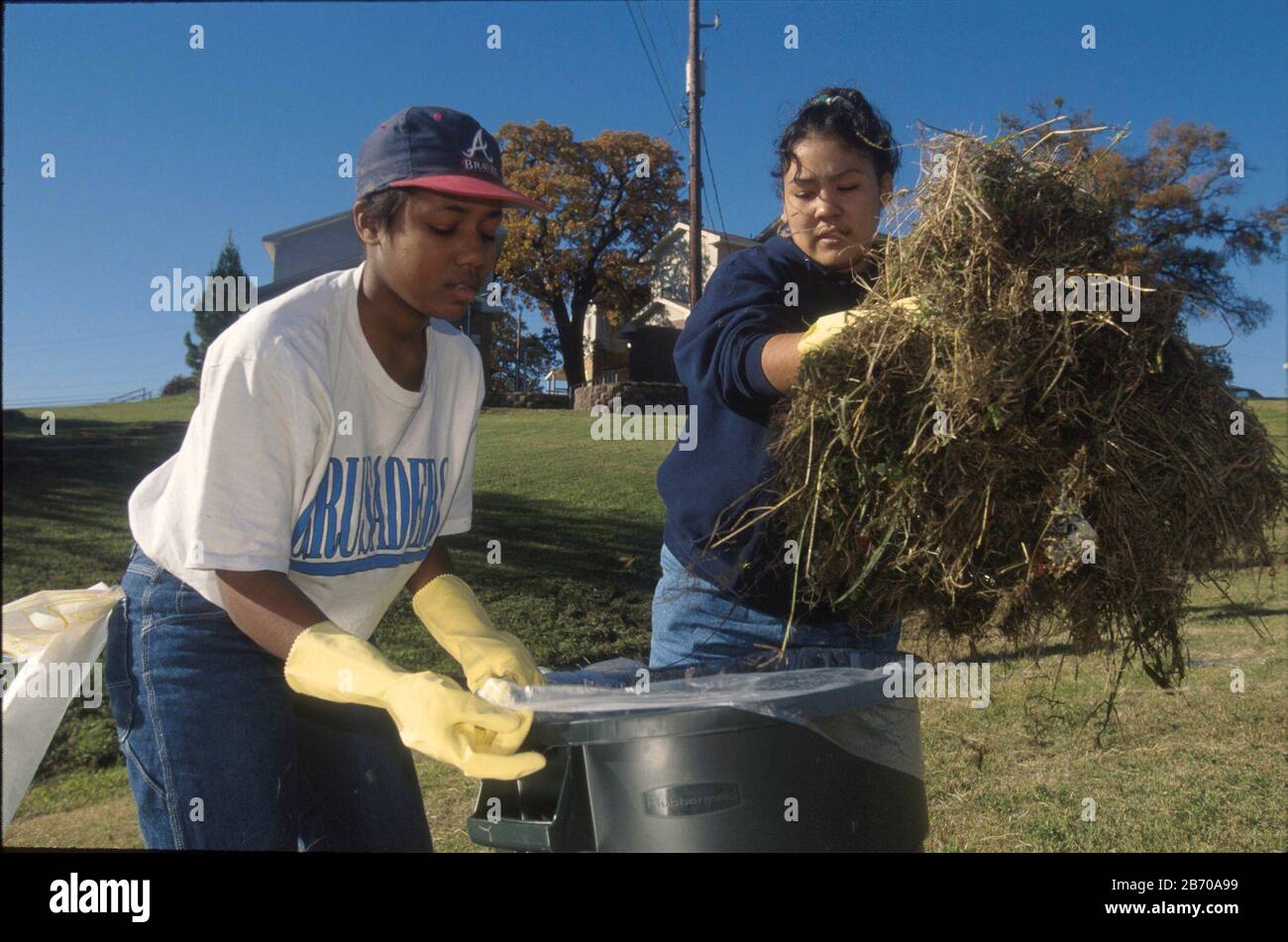 Austin, Texas, USA: Weibliche Studenten sammeln Müll auf dem Gelände des öffentlichen Wohnungsprojekts während des freiwilligen Reinigungstages. ©Bob Daemmrich Stockfoto