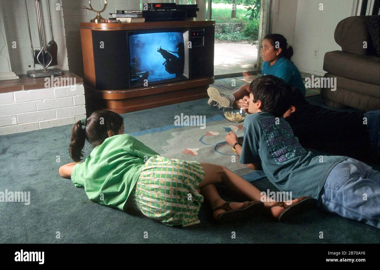 Austin Texas USA: Kinder sehen zu Hause ein gewalttätiges Fernsehprogramm (klassische westliche Schießerei) im Fernsehen. HERR ©Bob Daemmrich Stockfoto