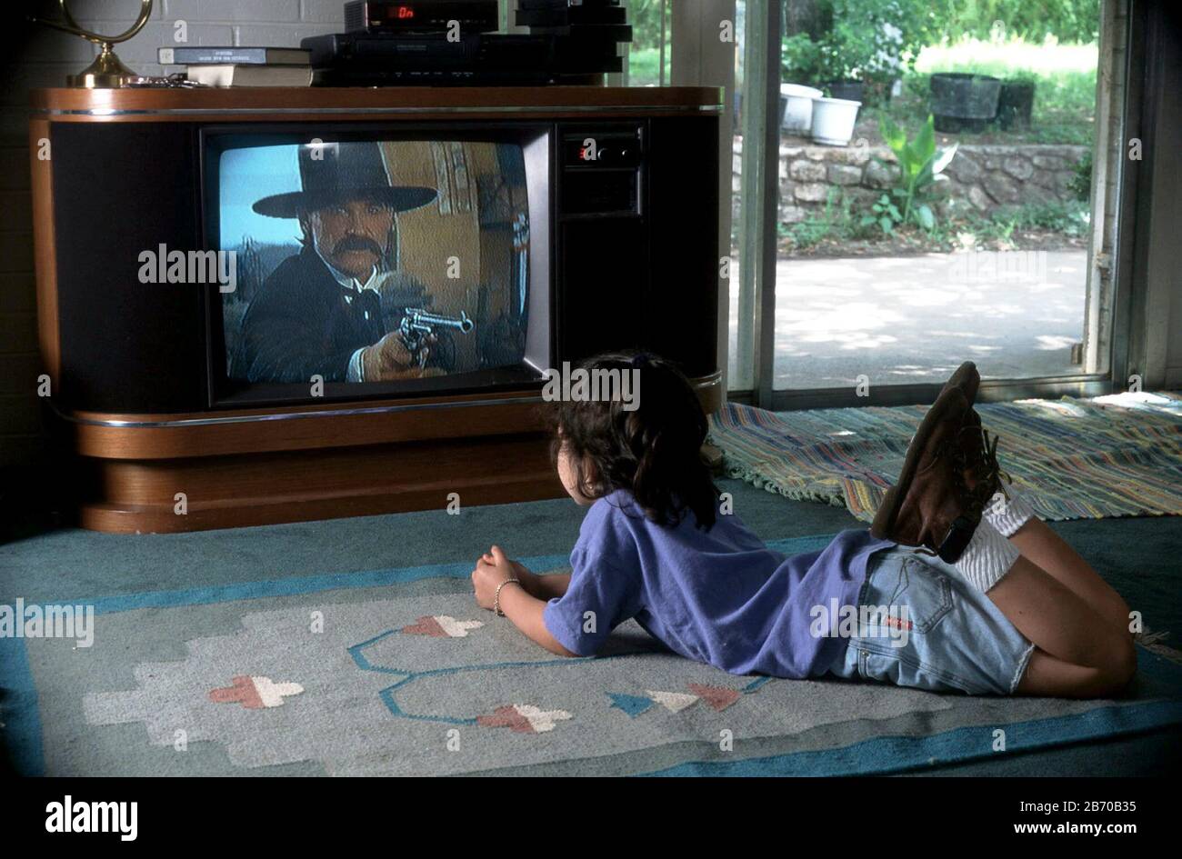 Austin Texas USA: Das achtjährige Mädchen sieht sich zu Hause ein gewalttätiges Fernsehprogramm (klassische westliche Schießerei) im Fernsehen an. HERR ©Bob Daemmrich Stockfoto