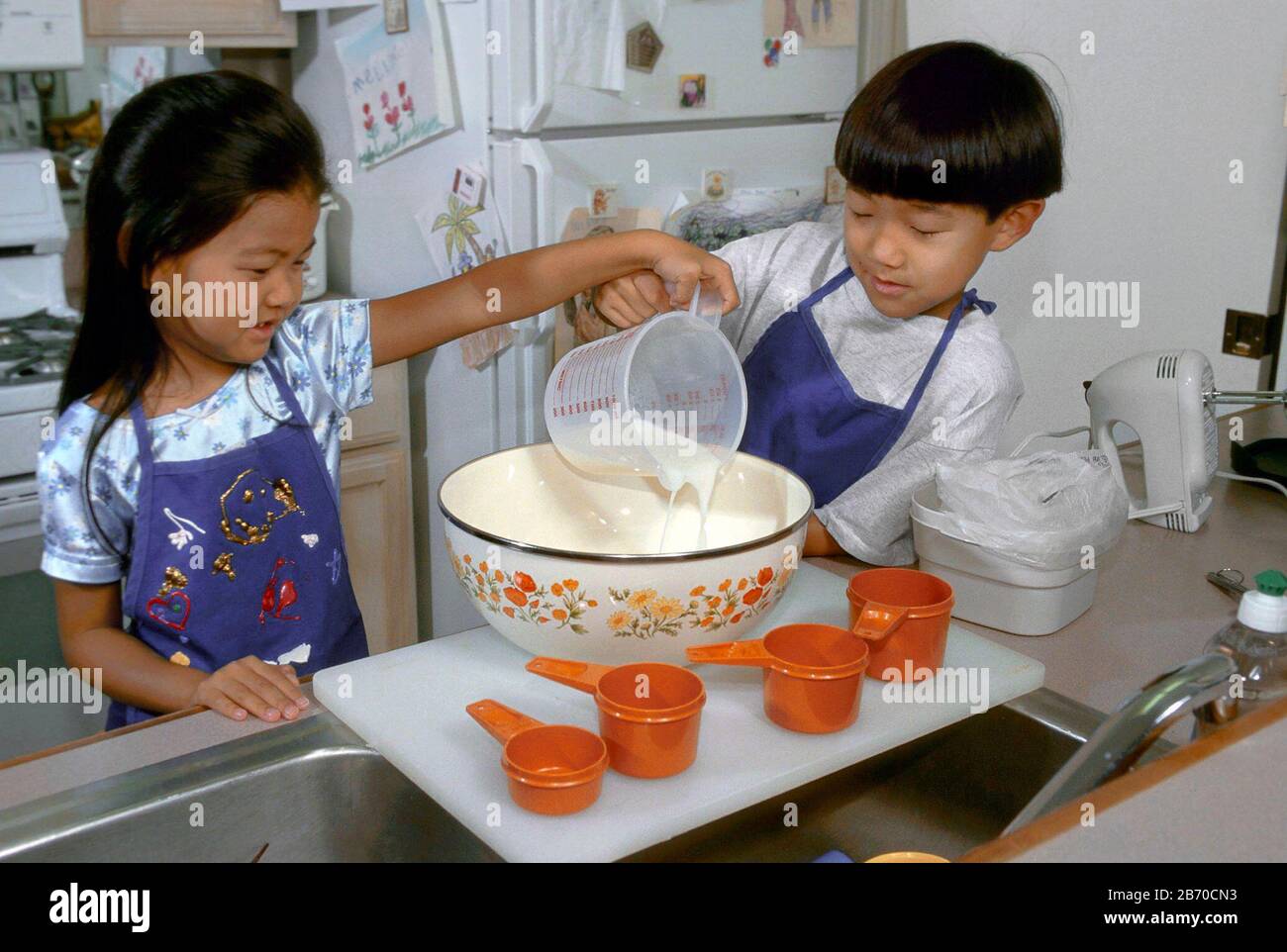 Austin, Texas, USA: Der siebenjährige asiatisch-amerikanische Junge mischt mit seiner sechsjährigen Schwester die Zutaten für Kuchen. HERR ©Bob Daemmrich Stockfoto