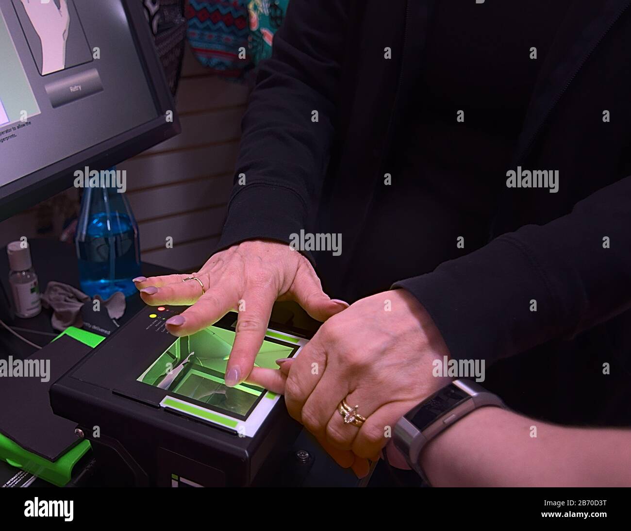 Eine junge Frau bekommt ihre Fingerabdrücke live gescannt, um einen Job als Berufstherapeutin für Reisen zu bekommen. Stockfoto