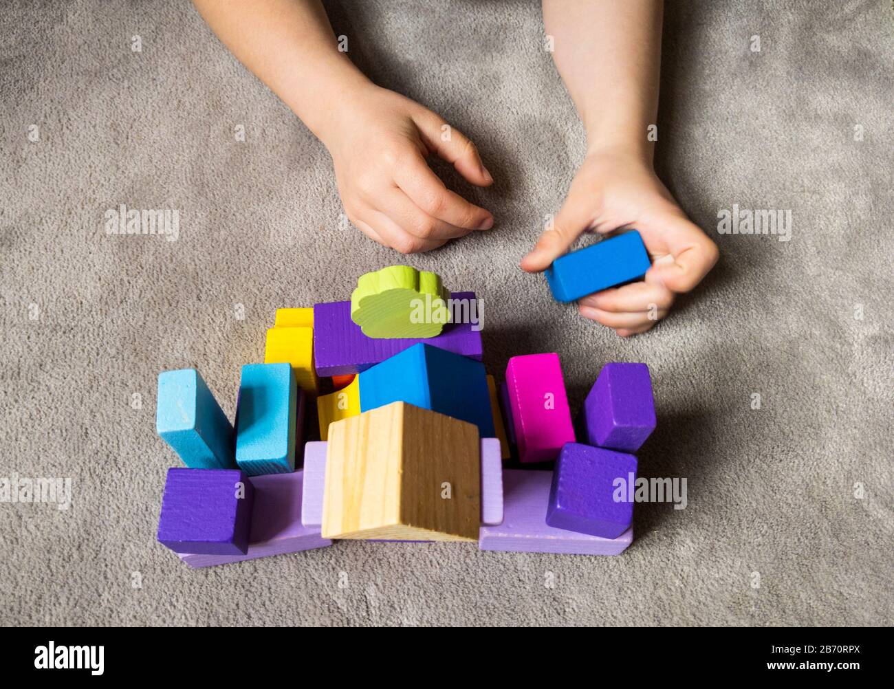 Ein Kind spielt mit farbenfrohem Herzen mit bunten Holzbausteinen. Weltautismus Bewusstsein Tag Konzept. Stockfoto