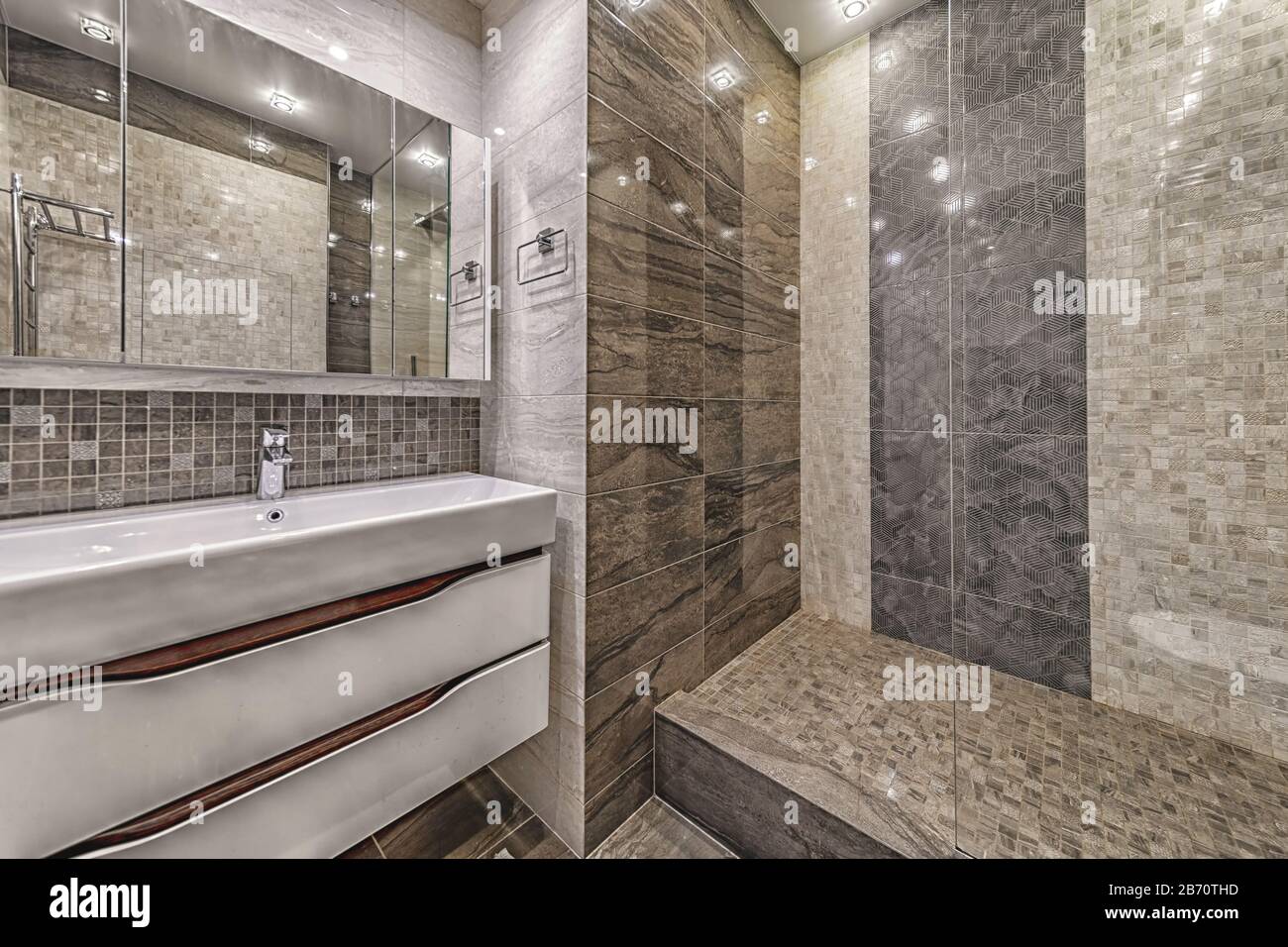 Modernes gefliestes Badezimmer: Einfaches weißes Waschbecken mit Schrank und durchsichtiger Glas-Duschtür Stockfoto