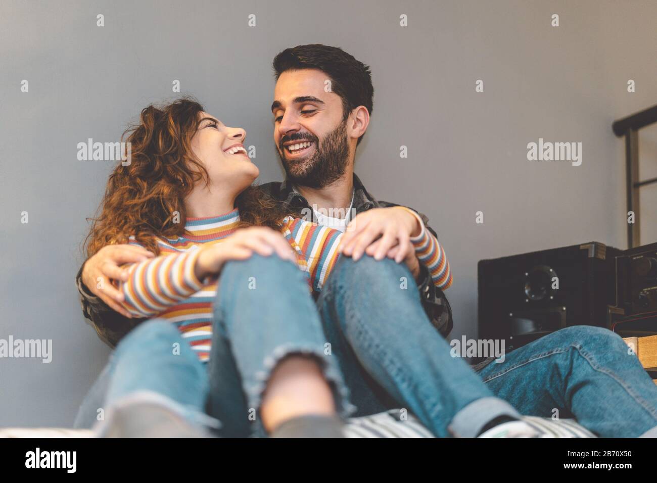 Glückliches Paar, das sich zu Hause im Wohnzimmer umarmt - Junge Liebhaber teilen zärtliche Momente zusammen - Liebesbeziehung und romantisches Anfängerkonzept Stockfoto