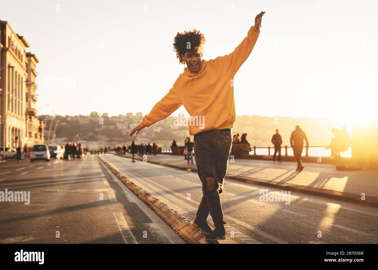 Afro American man hat Spaß beim gehen im Stadtzentrum - fröhlicher junger Kerl, der Zeit für einen Sonnenuntergang im Freien genießt Stockfoto