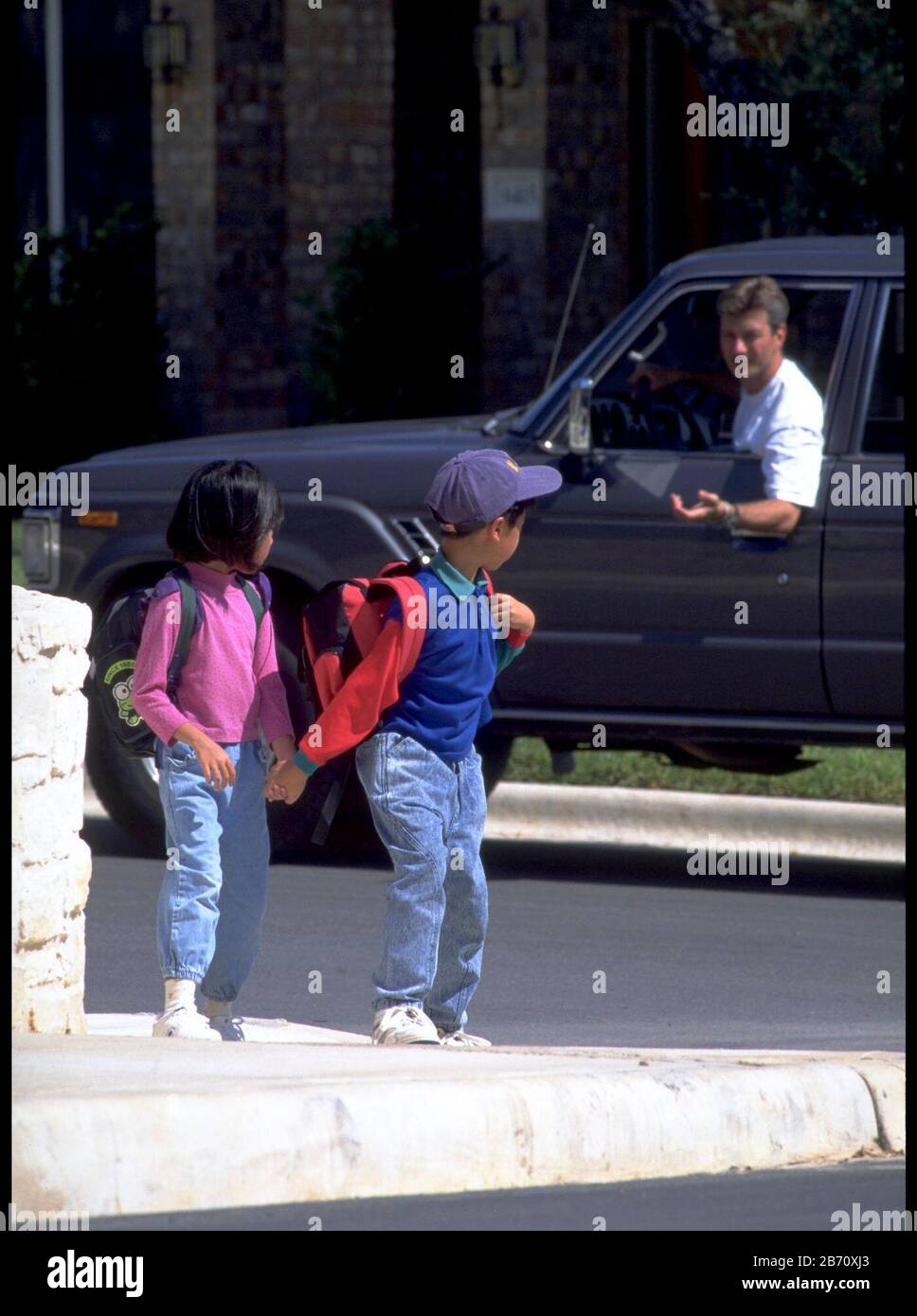 Austin Texas USA, 1993: Mädchen und Jungen der asiatisch-amerikanischen Grundschule gehen von Fremden weg und versuchen, sie in ein Fahrzeug zu locken, während sie von der Schule nach Hause gehen. ©Bob Daemmrich Stockfoto